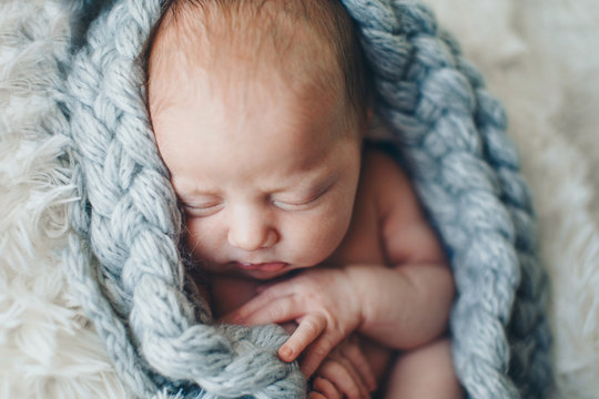 portrait of a little girl in a wool blanket. imitation of the umbilical cord, a baby in the womb. close-up of the child's face. concept of childhood, health care, IVF