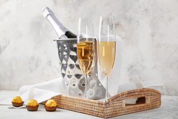 Bucket with ice and champagne on light background