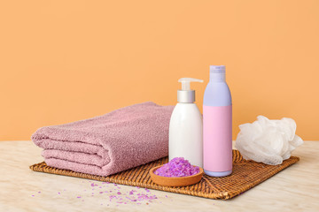 Obraz na płótnie Canvas Shower gels, towel, sea salt and loofah on color background