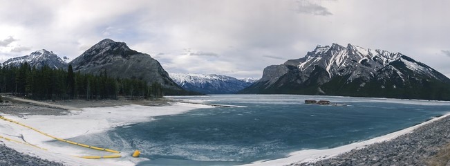 Lake Minnewanka Frozen Water Surface Panoramic Landscape on a cloudy day in Banff National Park,...