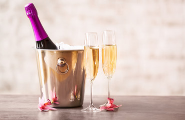 Bucket with ice and champagne on light background