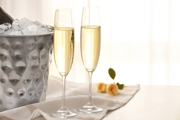 Bucket with ice and champagne on table in room