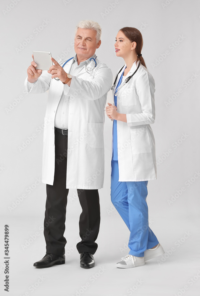 Poster doctors with tablet computer on grey background