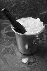 Bucket with ice and champagne on dark background