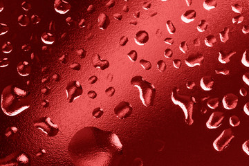 Water drops on window glass. Rain drops on gradient red background. Macro, closeup.