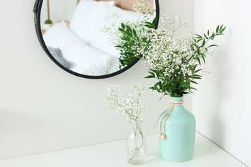Vases with flowers in modern bedroom