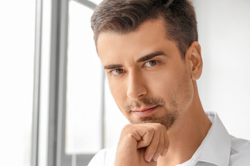 Portrait of handsome businessman near window in office
