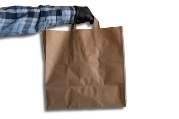 a man's hand in black gloves holds a paper bag on a white background, mock up paper bag, delivery concept