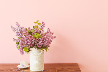 Beautiful lilac flowers on table against color background