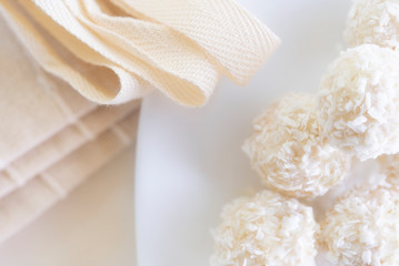 Candies in plate covered by chocolate, shredded coconut and kitchen towel on rustic wooden background.
