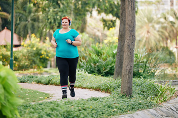 Plus size young woman enjoying running in park in the morning