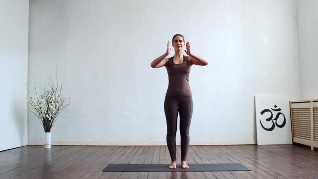 Young and fit woman practicing yoga indoor in the class. Stretching exercise in the day light. Sport, fitness, health care and lifestyle.