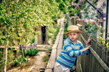 Naklejka na ściany i meble Portrait of a boy in a straw hat in the countryside