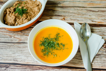 Traditional pumpkin soup with seeds, dill on a wooden table.