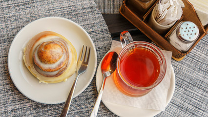 Sweet round bun and cup of tea on a beautiful napkin background. Bakery concept.