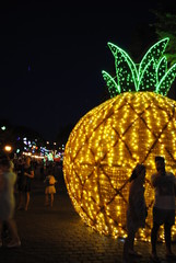 Night on the main street with the big lite instalation like pineapple and human silhouettes