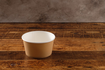 Big brown paper plate isolated on wooden background. Eco-friendly disposable food packaging. Preserving nature and recycling concept.