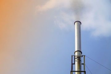 industrial pipes with black smoke against blue sky