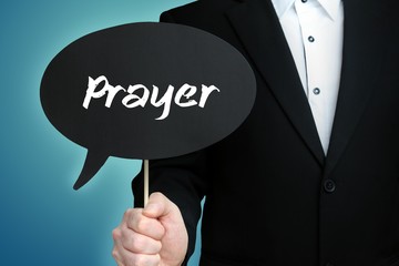 Prayer. Lawyer in suit holds speech bubble at camera. The term Prayer is in the sign. Symbol for law, justice, judgement