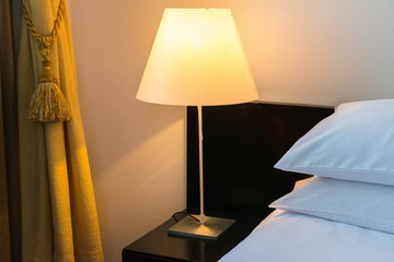 the bed in the room with pillows and duvet and the lighted lamps