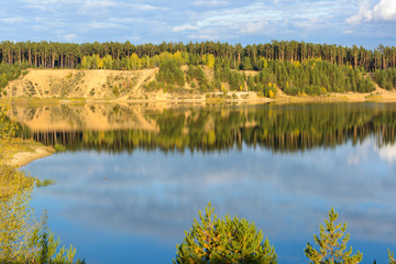 Emerald Lake with textural clouds, sandy mountains and forest. View from a high mountain.