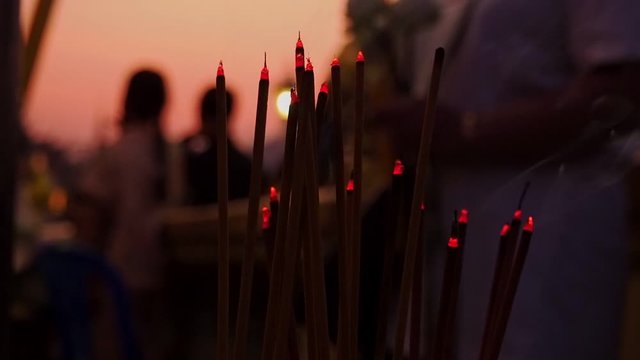 People in Cambodia burning incense to symbolize their faith and prayers to the heavens - close up