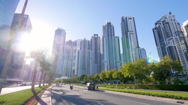 Street view of high rise buildings and bright white sun in downtown Dubai