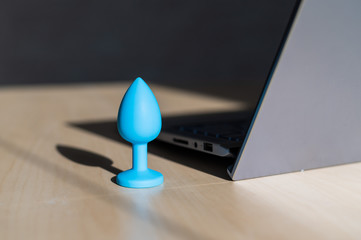 Blue latex anal plug the laptop on the table. The concept of virtual sex on the Internet. Anus...