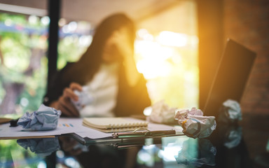 Businesswoman get stressed with screwed up papers and laptop on table while having a problem at work in office