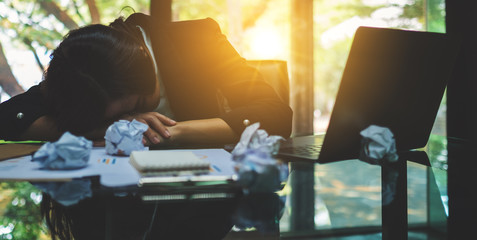 Businesswoman get stressed with screwed up papers and laptop on table while having a problem at...