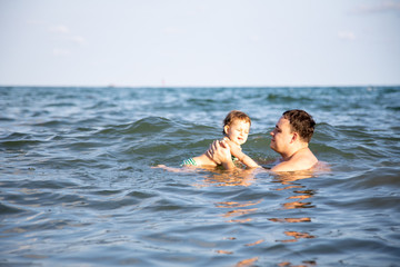 fatherly love concept. best dad. father teaches swiming a little cute toddler daughter in the water of a warm  sea.