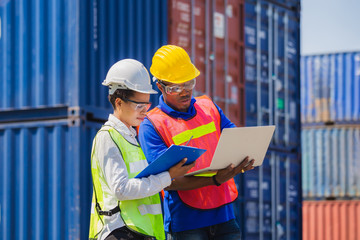 Female foreman safety vest using clipboard checklist and Worker man in hardhat holding laptop for control loading containers box from cargo