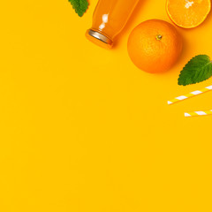 Glass bottles with orange juice, fresh sweet oranges, mint leaves and drinking tubs on yellow background. Healthy food, healthy drink, vitamin C. Creative summer concept. Flat lay top view copy space