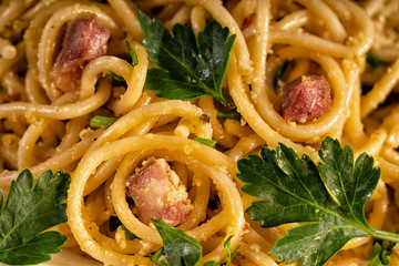 Cooked pasta carbonara with bacon pieces under egg sauce. Macro, closeup. Traditional italian...