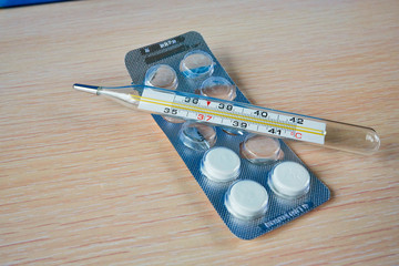 Mercury body thermometer and nearly finished pack of tablets. Back on one's feet. Macro view
