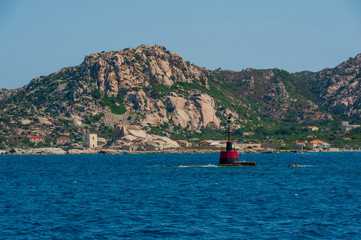 A view of a signal buoy for sailing into the sea on a sunny day with the coast of the island in the background, in Sardinia Italy