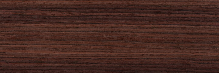 Contrast rosewood veneer background in dark color. Natural wood texture, pattern of a long veneer sheet, plank.