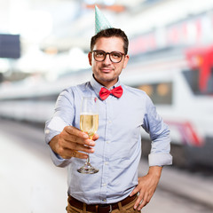 Man wearing a red bow tie and party hat. Offering a champagne glass.