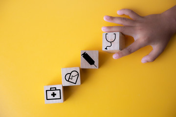 Children hands holding wood cube with a medical symbol,Concept: Health insurance family covid-2019 epidemic,.management protect healthcare to a virus,care service doctor treatment for hospital.