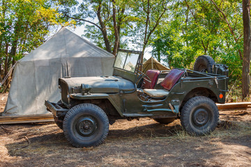 American world war II military four-wheel car Willys MB in a forest near an old canvas tent