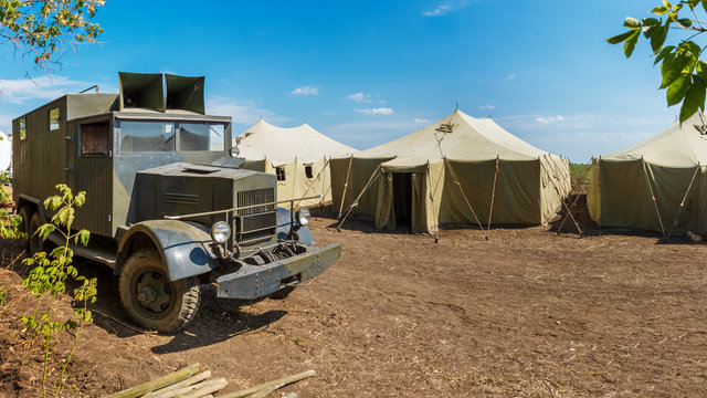 Retro german World War II military truck Krupp L3H163 is standing near a row of old canvas tents in a military camp