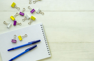 Notebook with pen and stationery clips on a light background