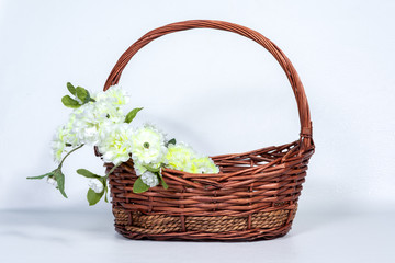 Fototapeta na wymiar Brown wicker basket with flower arrangements on the handle of the basket.