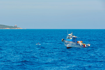 A view of a fishing boat at work in the blue Mediterranean sea on a sunny day in summer, in Sardinia Italy