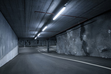 Sci fi looking dark and moody underground parking lot with fluorescent lights on.  Low wide angle...