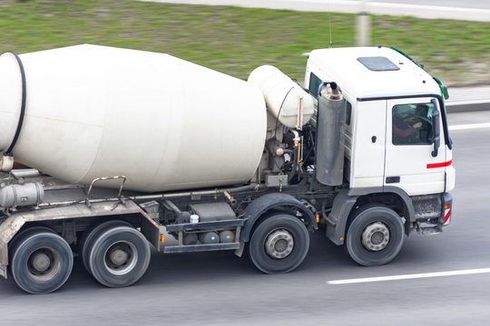 Concrete white mixer truck rides on city highway.