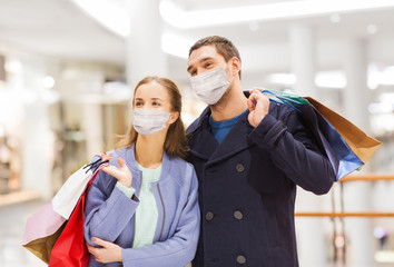 sale, consumerism and pandemic concept - happy young couple wearing face protective medical mask...