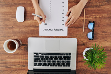 Woman writing weekly planner to stay productive when working from home during quarantine period