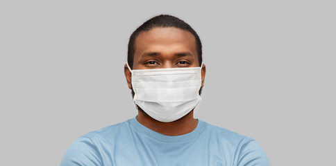 health, pandemic and safety concept - young african american man wearing face medical mask for protection from virus disease over grey background