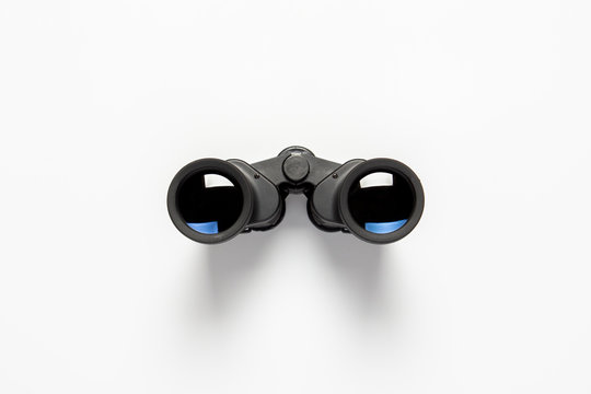 Black binoculars on a white background. Flat lay, top view